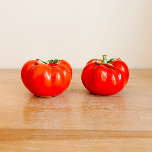 Two red tomatoes on a wooden surface with a beige background